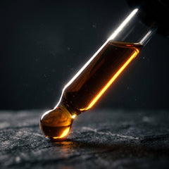 Amber oil glowing inside a dark glass dropper