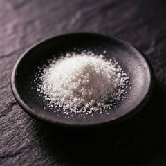 Fine white crystalline powder in a small black dish