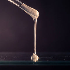 A clear viscous gel drawing a thread from a glass rod