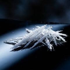 Needle-like white crystals on a black mirrored surface
