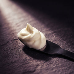 A swirl of white cream on a matte black spatula